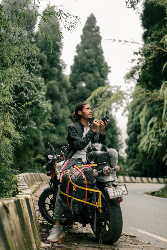Man on motorcycle with camera exploring lush forests in Darjeeling, India.