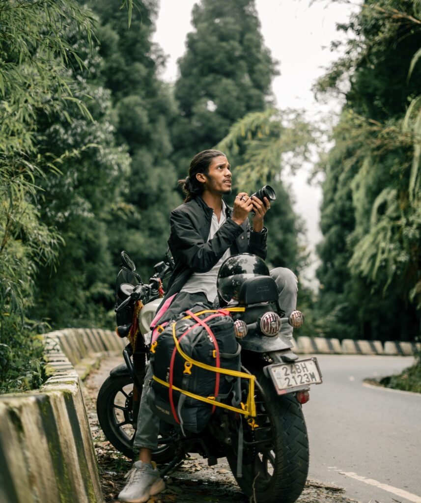 Man on motorcycle with camera exploring lush forests in Darjeeling, India.